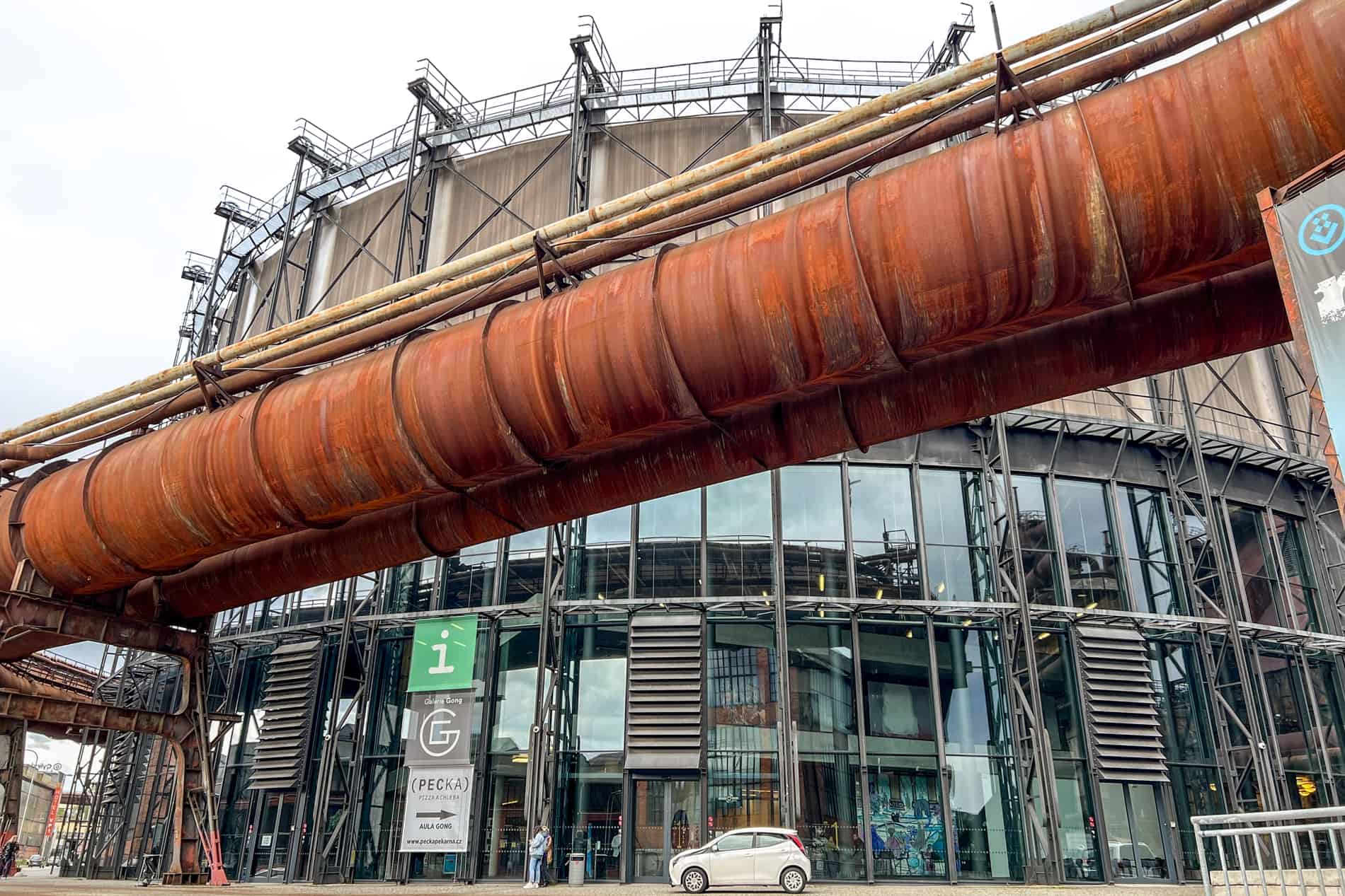A repurposed round building at the former ironworks site of Dolní Vitkovice behind a huge rusting pipe. 
